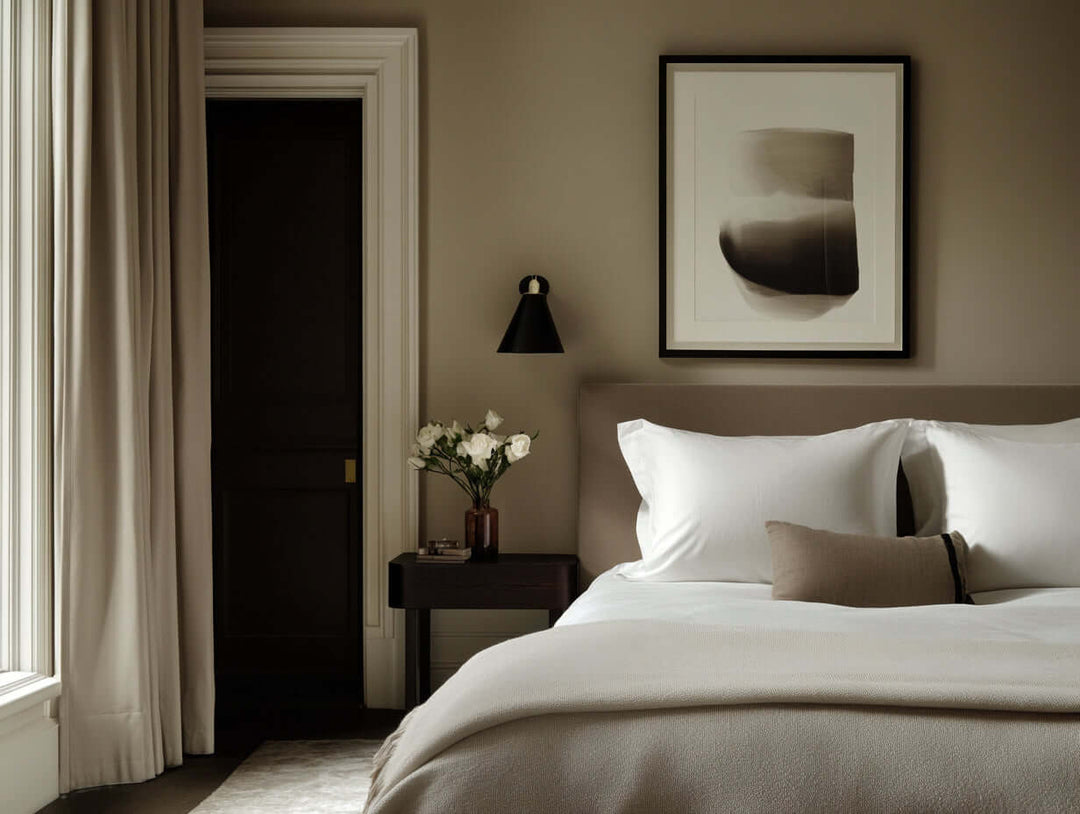 Serene bedroom with a bed dressed in soft, white Egyptian cotton sheets and a beige duvet, as discussed in a guide to buying Egyptian cotton bedding.
