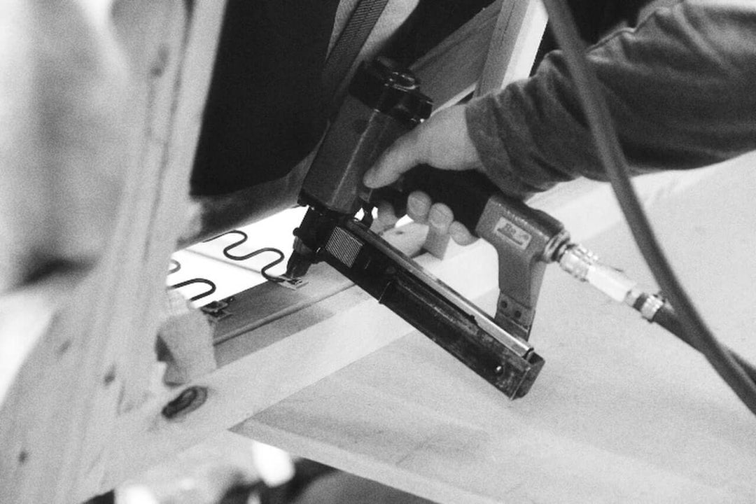 Artisanal sofa frame construction, luxurious fabric swatches, close-up of hand-stitched upholstery.