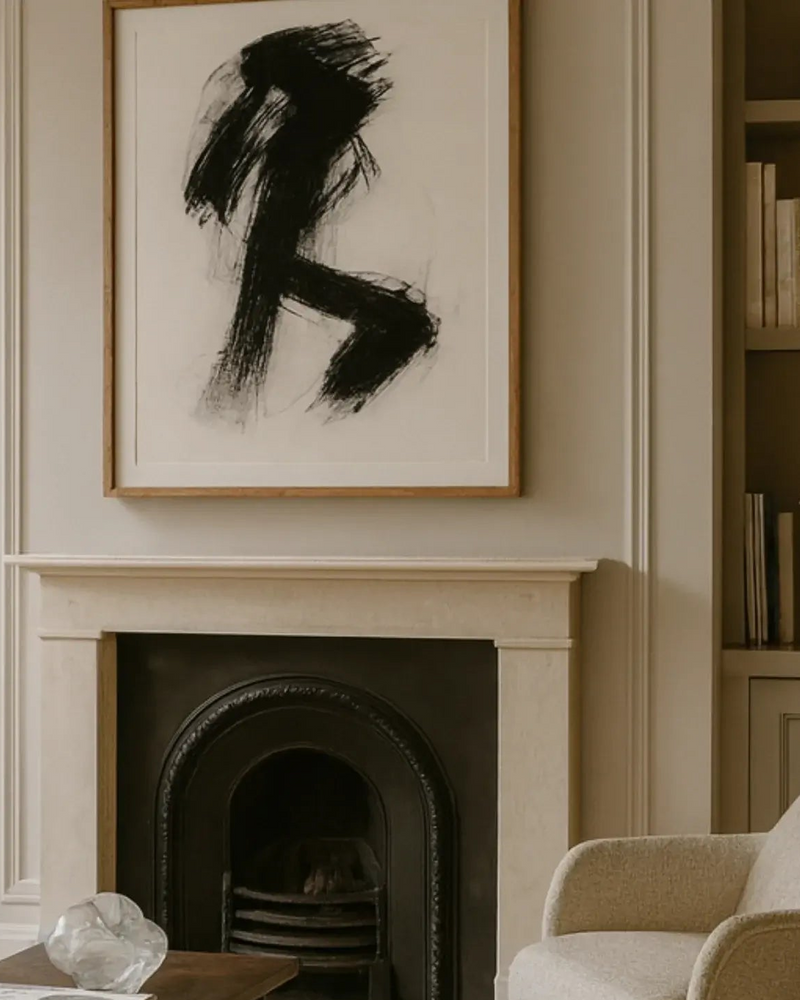Abstract black and white painting above a fireplace in a room with a bookshelf.