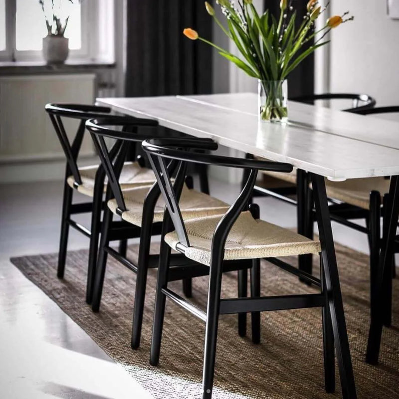Dining table with balck wishbone chairs in dining area - Escapology Home
