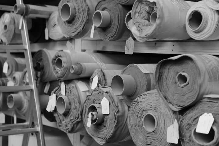Stack of sofa upholstery fabric rolls with tags on a rack